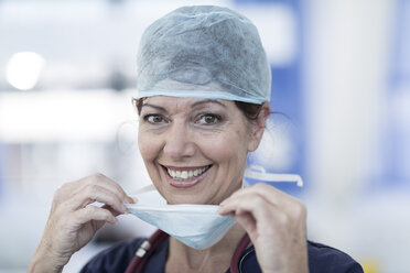 Portrait of smiling doctor in hospital wearing surgical mask - ZEF006117