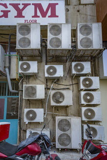 UAE, Dubai, several air conditioning units on a wall in a back road - NKF000309