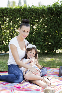 Portrait of mother and her little daughter sitting on a blanket - GDF000818