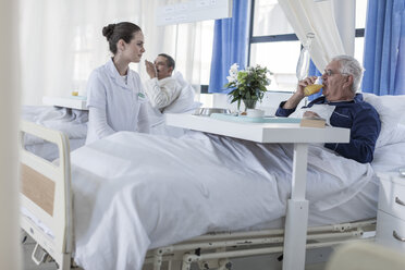 Krankenschwester betrachtet älteren Patienten im Krankenhausbett - ZEF006779