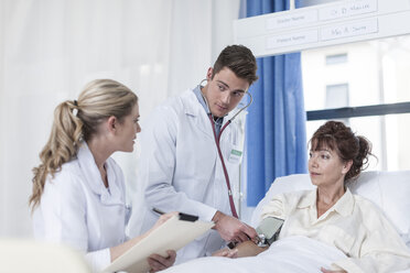 Arzt und Krankenschwester untersuchen eine Frau im Krankenhausbett - ZEF006789