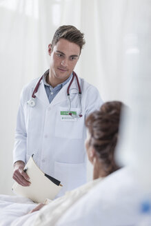 Doctor smiling at woman in hospital bed - ZEF006791