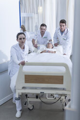 Krankenhauspersonal schiebt Bett mit Patient auf dem Boden - ZEF006794
