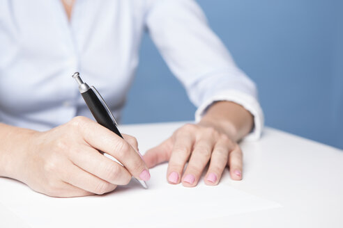 Frau beim Unterschreiben eines Dokuments auf dem Tisch - VTF000432
