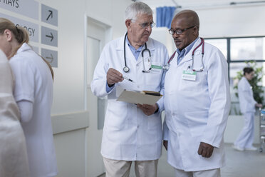 Zwei Ärzte im Krankenhauskorridor besprechen eine Patientenakte - ZEF006811