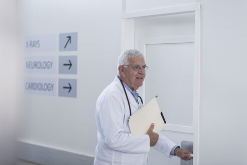 Doctor in hospital corridor opening door - ZEF006817