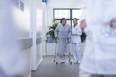Krankenschwester hilft Patientin mit Gehhilfe im Krankenhausflur - ZEF006824