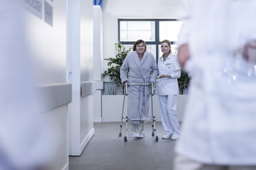 Nurse helping patient with walking frame in hospital corridor - ZEF006824