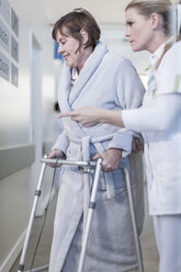 Nurse helping patient with walking frame in hospital corridor - ZEF006825