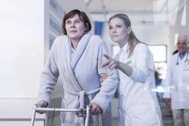 Nurse helping patient with walking frame in hospital corridor - ZEF006826