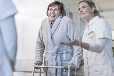 Nurse helping patient with walking frame in hospital corridor - ZEF006827