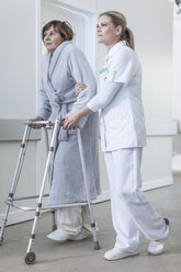 Nurse helping patient with walking frame in hospital corridor - ZEF006828