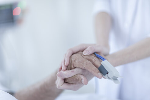 Finger heart monitor on patient, nurse holding hands - ZEF006546