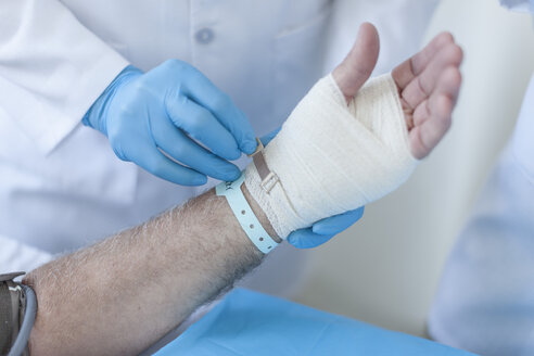 Krankenschwester beim Verbinden einer Wunde an der Hand eines Patienten - ZEF006558