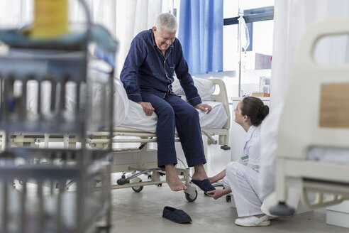 Krankenschwester, die einen älteren Patienten im Krankenhausbett pflegt - ZEF006835