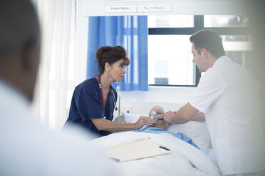 Arzt und Krankenschwester legen einem Patienten im Krankenhausbett eine Sauerstoffmaske an - ZEF006844