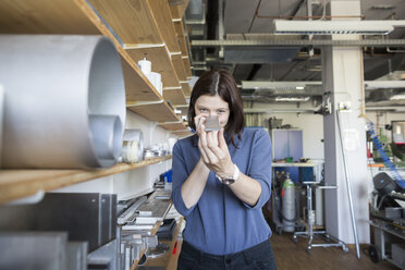 Young woman in workshop examining metal piece - SGF001767