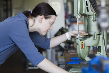 Junge Frau in der Werkstatt bei der Arbeit mit einer Sägemaschine - SGF001769