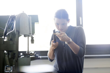 Junge Frau in der Werkstatt bei der Arbeit mit einem Ordner - SGF001780