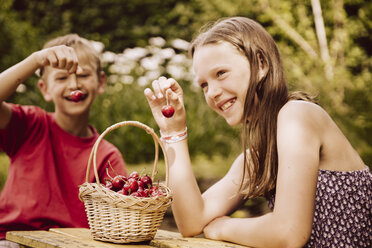 Girl and boy enjoying cherries in garden - MFF001880