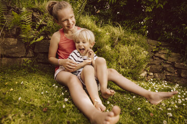 Mädchen kitzelt kleinen Jungen im Garten - MFF001890