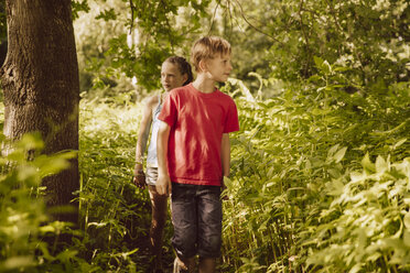 Zwei Kinder wandern durch Himalaya-Balsam in einem Wald - MFF001905