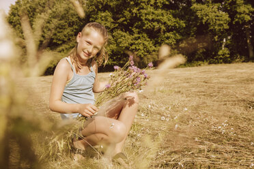 Mädchen pflückt Blumen auf einem Feld - MFF001911