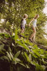 Little boy and girl balancing on fallen tree in forest - MFF001925