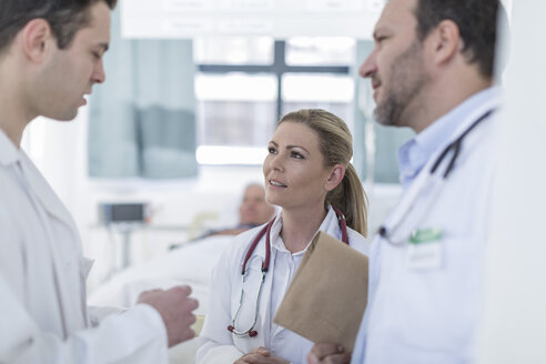 Drei Ärzte kommunizieren in einem Krankenhauszimmer - ZEF006233