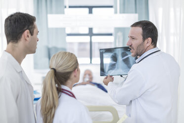 Three doctors with x-ray image in a hospital room - ZEF006237