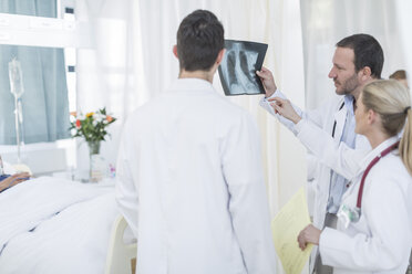 Three doctors looking at x-ray image in a hospital room - ZEF006239