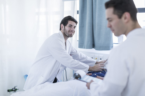 Zwei Ärzte untersuchen einen Patienten in einem Krankenhauszimmer, lizenzfreies Stockfoto