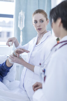 Porträt einer Krankenschwester, die den Arm eines Patienten im Krankenhaus verbindet - ZEF006261
