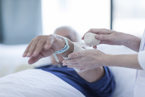 Krankenschwester bandagiert Arm eines älteren Mannes in einem Krankenhaus, Nahaufnahme - ZEF006262