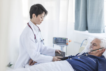 Doctor taking blood pressure of senior man with oxygen mask in a hospital - ZEF006267