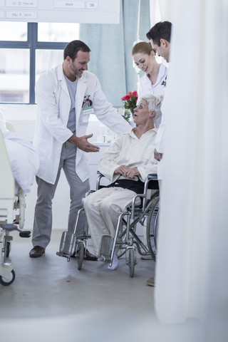 Arzt und Personal helfen einem Patienten mit Rollstuhl im Krankenhaus, lizenzfreies Stockfoto
