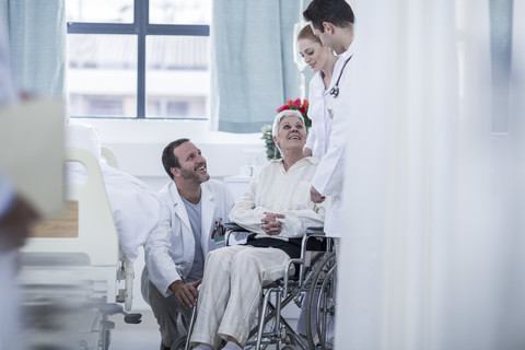 Arzt und Personal helfen einem Patienten mit Rollstuhl im Krankenhaus, lizenzfreies Stockfoto