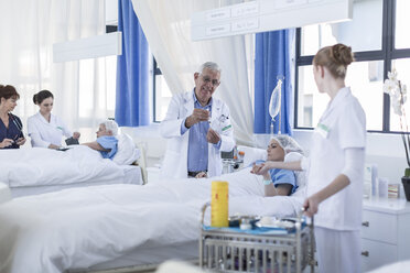 Doctor and nurse at very sick patient's bed in hospital - ZEF006877