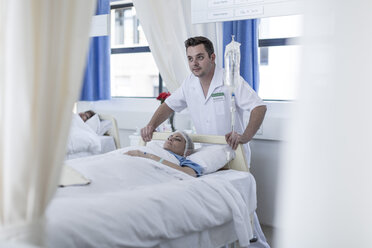 Krankenschwestern bewegen einen im Bett liegenden Patienten - ZEF006885