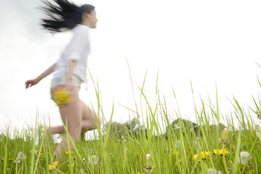Junge Frau läuft auf einer Wiese - BFRF001370