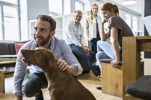 Kollegen mit Hund im Büro, lizenzfreies Stockfoto