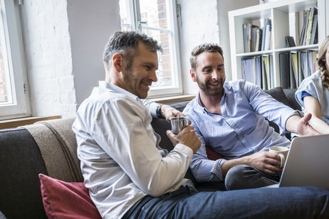 Zwei lächelnde Geschäftsleute teilen sich einen Laptop, lizenzfreies Stockfoto