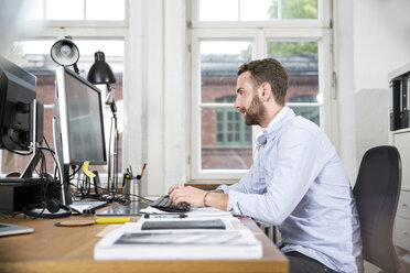 Junger Mann im Büro bei der Arbeit am Computer - FKF001323