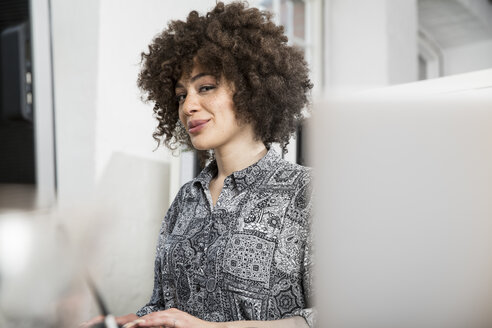 Lächelnde junge Frau im Büro am Schreibtisch - FKF001245