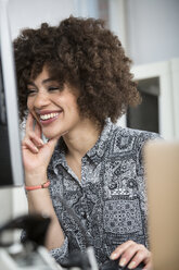 Happy young woman in office at desk - FKF001247
