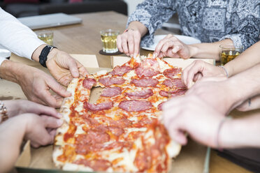 Kollegen im Büro teilen sich eine Pizza - FKF001275