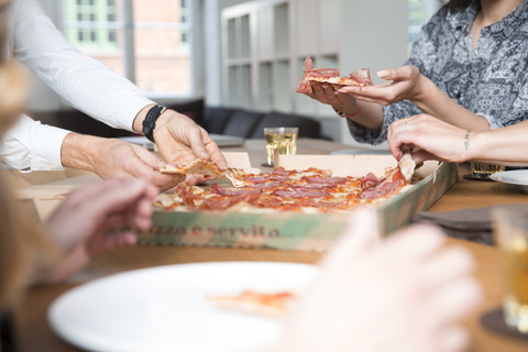 Kollegen im Büro teilen sich eine Pizza, lizenzfreies Stockfoto