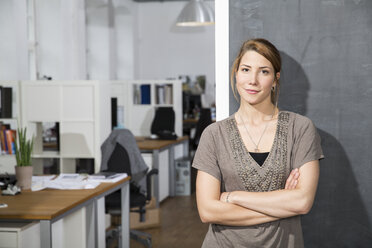 Smiling young woman standing at blackboard in office - FKF001294