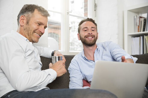Two smiling businessmen sharing laptop - FKF001305
