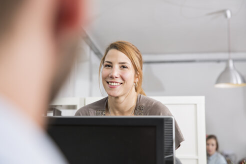 Portrait of smiling young woman with colleagues in office - FKF001308